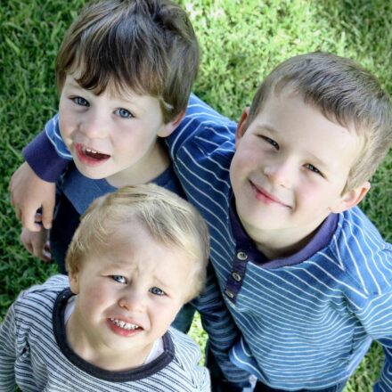 Three young children looking and smiling up at the camera