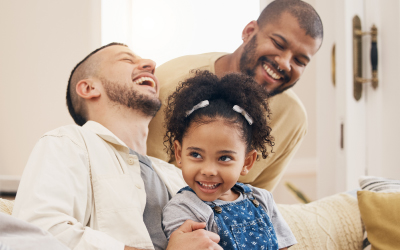 family and child laughing, sat on a home sofa