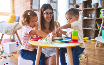 Young teacher and toddlers playing meals using plastic food and cutlery toy at playgroup
