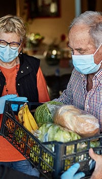 An elderly man holding a box of food