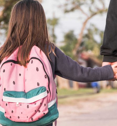 young girl holding a mans hand facing away