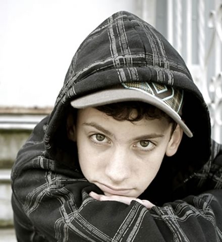 photo of a teenage boy wearing a hoody with his arms crossed