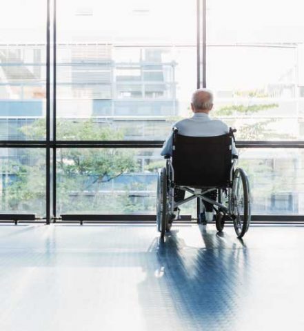 senior man in a wheelchair looking out of a window