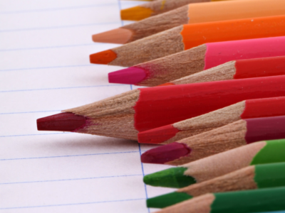 A set of colourful pencils on a page of lined paper