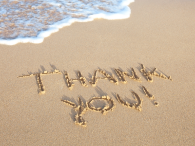 The words thank you written in the sand on a beach
