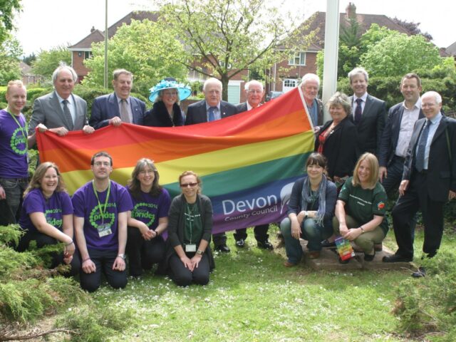 DCC Staff holding up a rainbow flag smiling