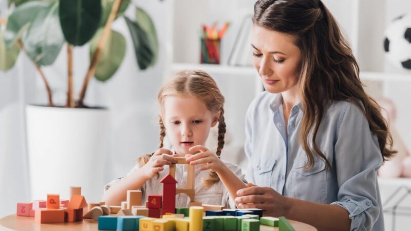 mother and daughter sat at a table playing with building blocks