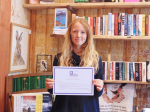 Kayleigh Diggle of Liznojan Books in Tiverton is the first business to sign up to the scheme, pictured holding her certificate