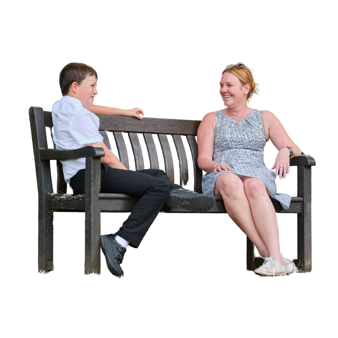 An adult talks to a child while sitting facing each other on a bench.